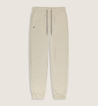 A pair of cream-colored textured knit jogger pants with a drawstring waist and elastic cuffs, shown flat on a light beige background.
