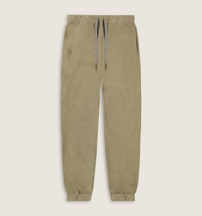 A pair of relaxed-fit jogger pants in a muted khaki-beige color, featuring a matching fabric waistband, elastic cuffs, and a decorative braided drawstring with a small gold button accent.